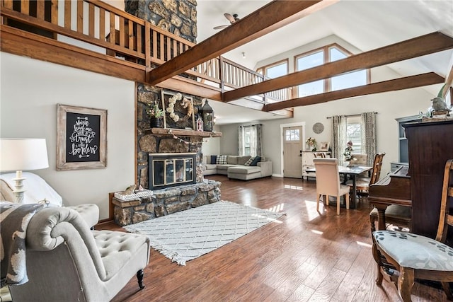 living room featuring hardwood / wood-style flooring, baseboards, beamed ceiling, and a stone fireplace