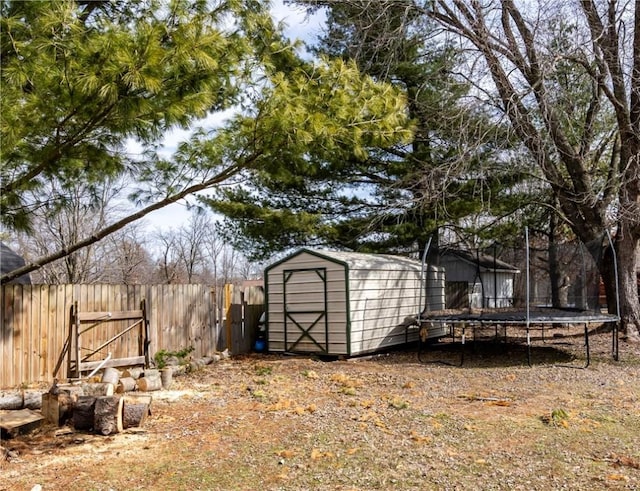 view of shed with a trampoline and fence