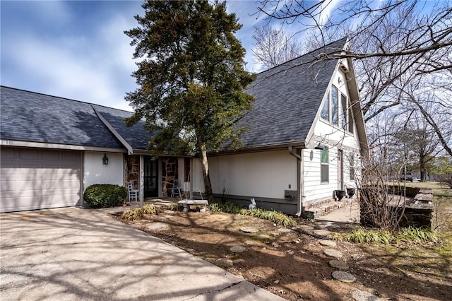 view of front of property featuring a garage, roof with shingles, and driveway