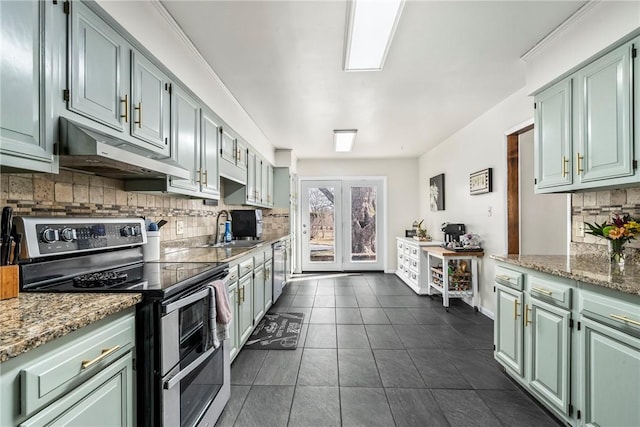 kitchen featuring stainless steel appliances, a sink, light stone countertops, green cabinetry, and under cabinet range hood