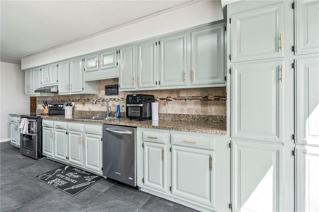 kitchen featuring tasteful backsplash, appliances with stainless steel finishes, a sink, dark stone countertops, and under cabinet range hood