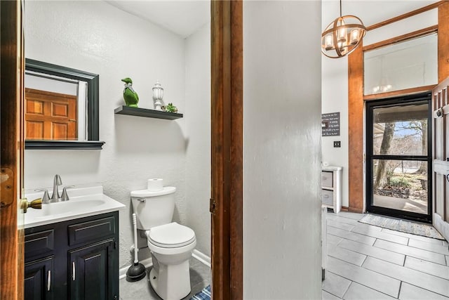 half bath with baseboards, vanity, and toilet