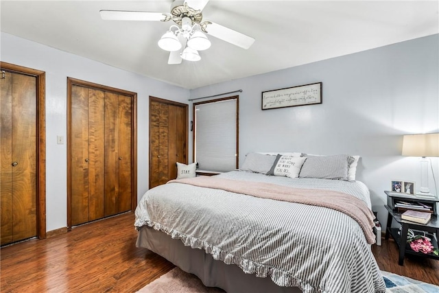 bedroom with ceiling fan, wood finished floors, and two closets