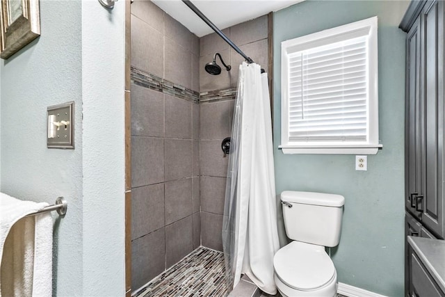 bathroom with a shower stall, toilet, and baseboards