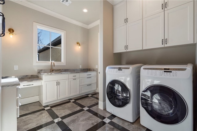 laundry area featuring cabinets, sink, ornamental molding, and washing machine and clothes dryer