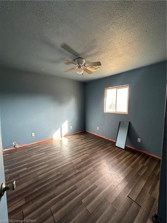 spare room with ceiling fan, dark hardwood / wood-style floors, and a textured ceiling