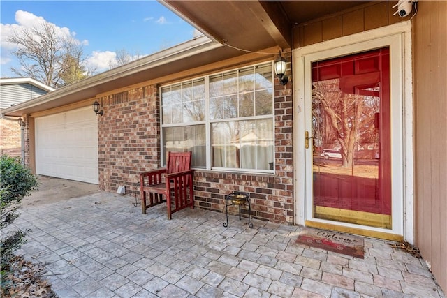 doorway to property featuring a garage and brick siding