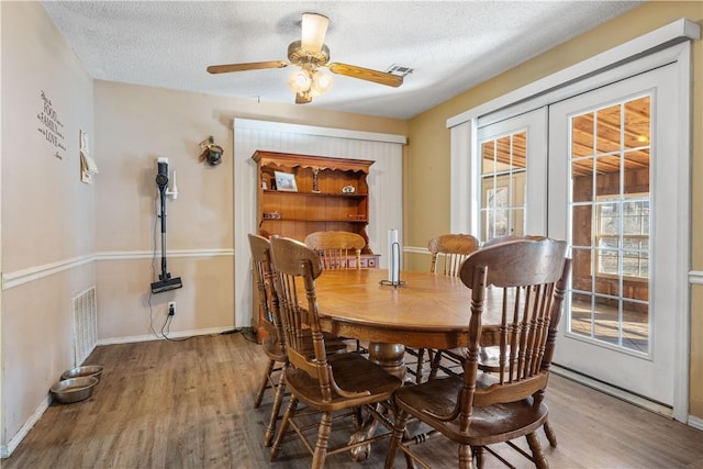 dining room with visible vents, a textured ceiling, and wood finished floors