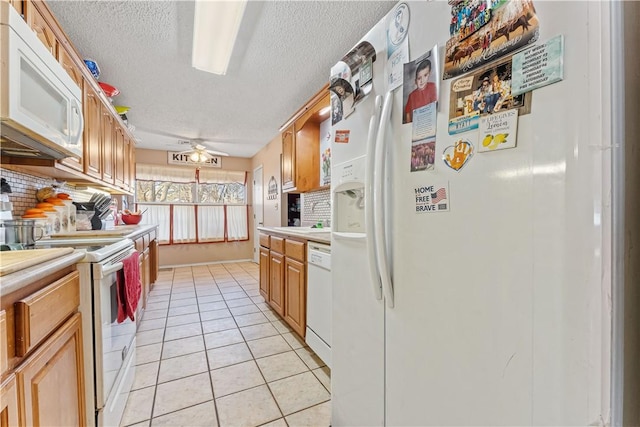 kitchen with light tile patterned floors, a textured ceiling, white appliances, light countertops, and decorative backsplash