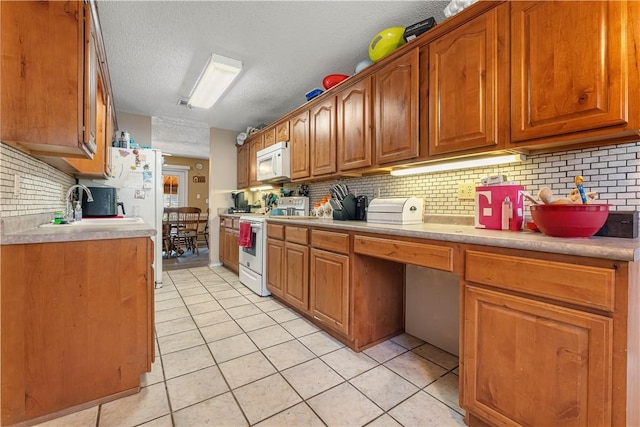 kitchen featuring brown cabinets, white appliances, light tile patterned floors, and light countertops