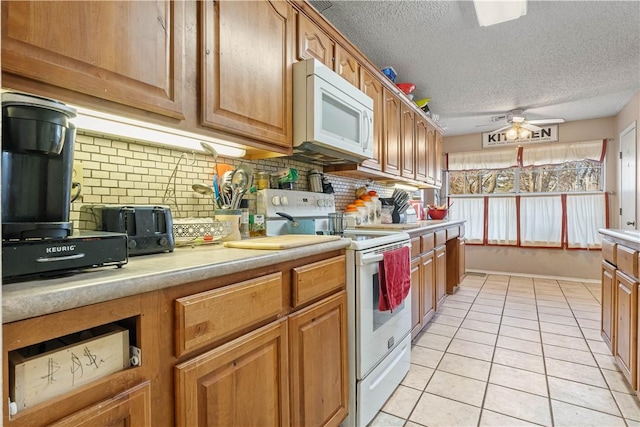 kitchen with a textured ceiling, ceiling fan, light tile patterned flooring, white appliances, and light countertops