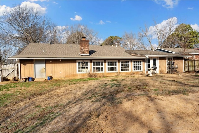 back of property with a chimney and fence