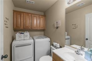 clothes washing area with washer and clothes dryer, visible vents, a sink, and laundry area