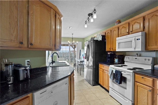 kitchen with light tile patterned floors, white appliances, a sink, and brown cabinets