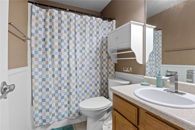 full bathroom featuring a wainscoted wall, a shower with curtain, toilet, vanity, and tile patterned flooring