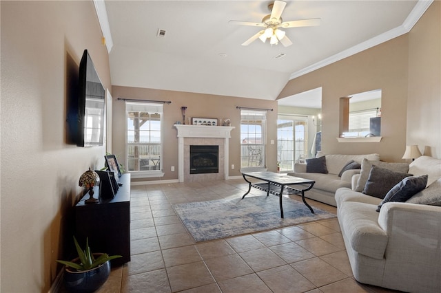 living room with lofted ceiling, light tile patterned floors, a tile fireplace, a ceiling fan, and ornamental molding