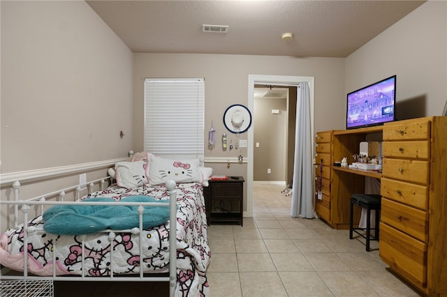 bedroom featuring tile patterned flooring, visible vents, and a textured ceiling