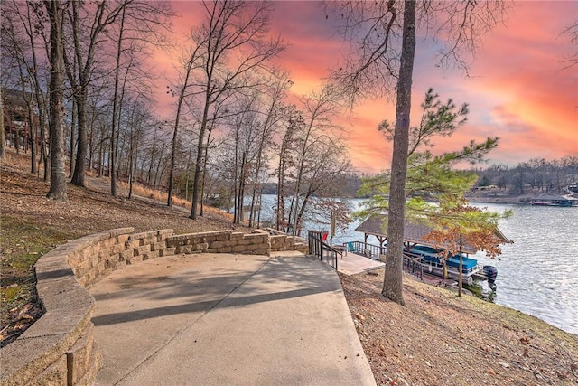 view of road with concrete driveway and a water view