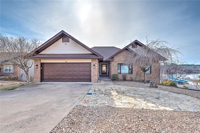 view of front of property featuring a garage, driveway, roof with shingles, and brick siding