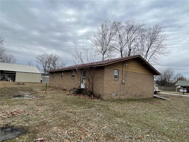 rear view of property featuring crawl space, brick siding, and a lawn