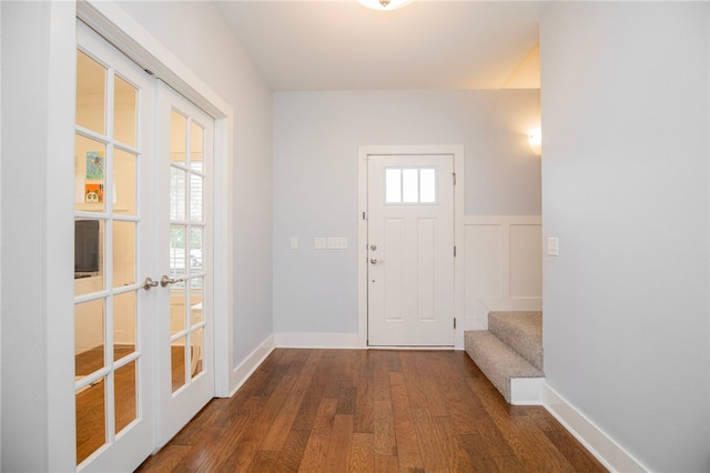 foyer featuring wainscoting, a decorative wall, dark wood-style flooring, and french doors