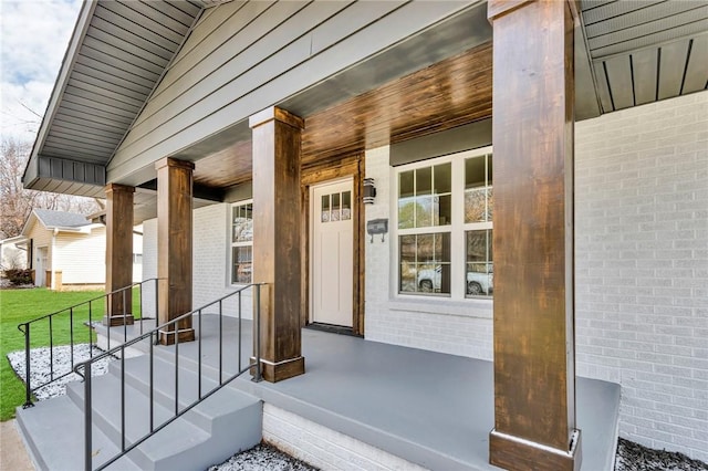 doorway to property featuring covered porch and brick siding