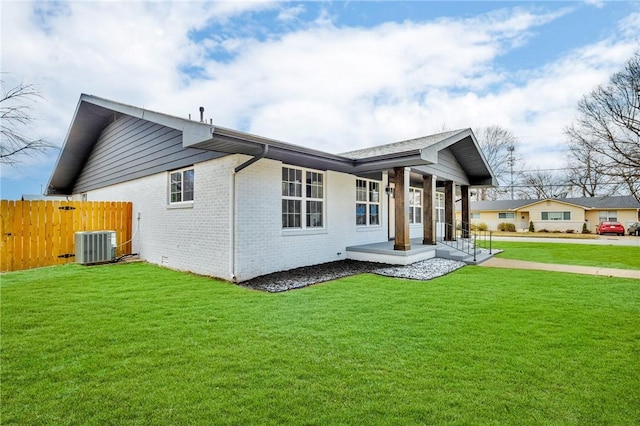 back of house with a yard, fence, central AC, and brick siding