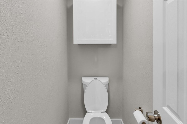 bathroom with toilet and a textured wall