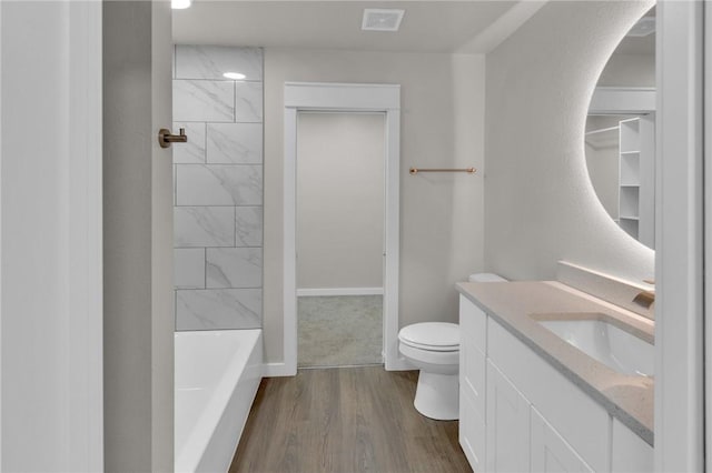 bathroom featuring visible vents, toilet, vanity, wood finished floors, and baseboards