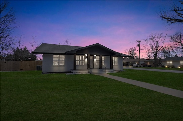 view of front of home with a lawn and fence