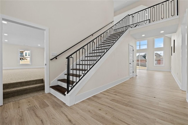 staircase with a towering ceiling, baseboards, and wood finished floors