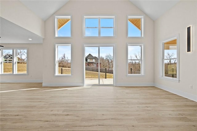 interior space with high vaulted ceiling, light wood-type flooring, and baseboards