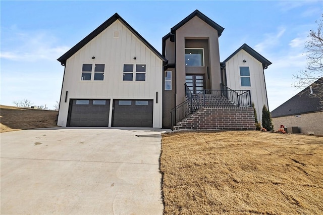 modern inspired farmhouse with a garage, concrete driveway, board and batten siding, and central AC