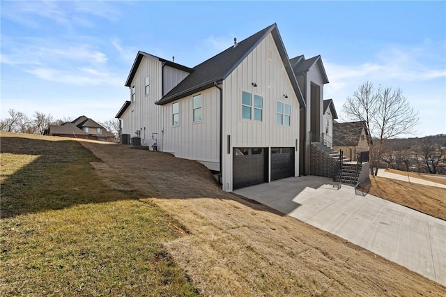 view of side of home with driveway, an attached garage, stairs, a yard, and board and batten siding