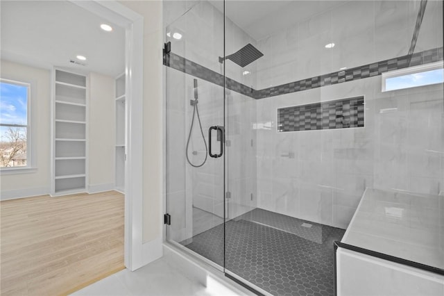 bathroom featuring baseboards, wood finished floors, a shower stall, and a healthy amount of sunlight