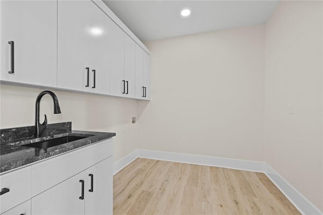 washroom featuring hookup for a washing machine, a sink, light wood finished floors, and baseboards