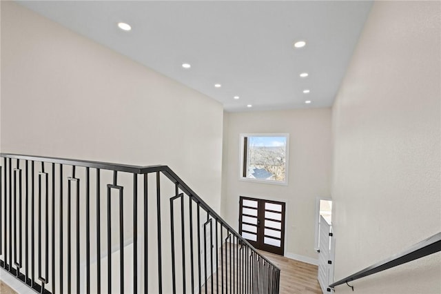 stairs with french doors, recessed lighting, a high ceiling, wood finished floors, and baseboards