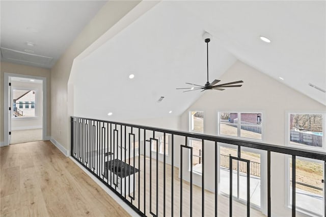 corridor with lofted ceiling, light wood-style floors, baseboards, and visible vents