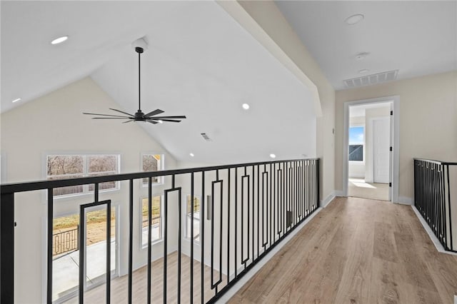 hallway with visible vents, baseboards, light wood-type flooring, high vaulted ceiling, and recessed lighting