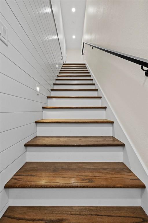 stairs featuring wood walls and recessed lighting