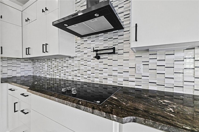 kitchen featuring tasteful backsplash, black electric cooktop, wall chimney exhaust hood, and white cabinets