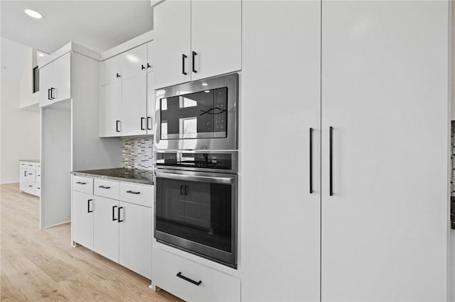 kitchen featuring light wood-style floors, dark countertops, decorative backsplash, and white cabinets