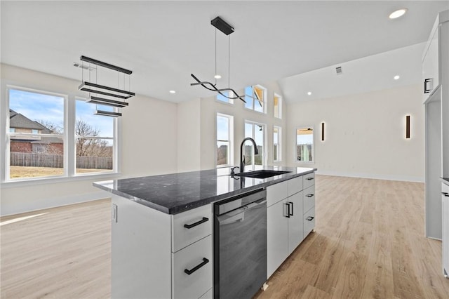 kitchen with light wood-style flooring, white cabinets, black dishwasher, a center island with sink, and pendant lighting