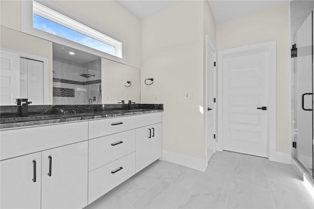 full bath featuring a sink, a shower stall, baseboards, and double vanity