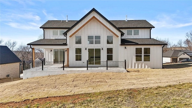 back of house with a patio area, a yard, board and batten siding, and roof with shingles