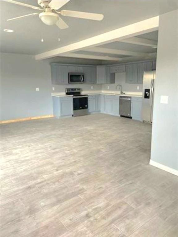 kitchen with light countertops, gray cabinetry, appliances with stainless steel finishes, beamed ceiling, and baseboards