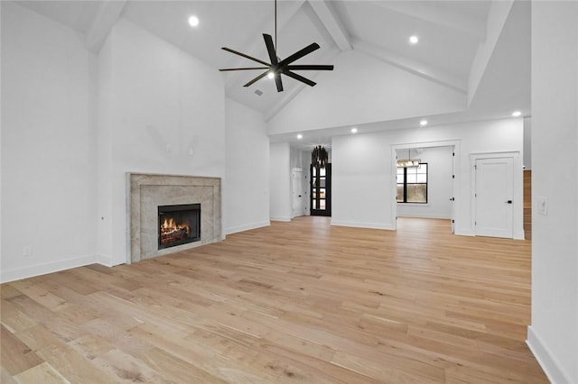 unfurnished living room featuring high vaulted ceiling, a high end fireplace, beam ceiling, and light wood finished floors