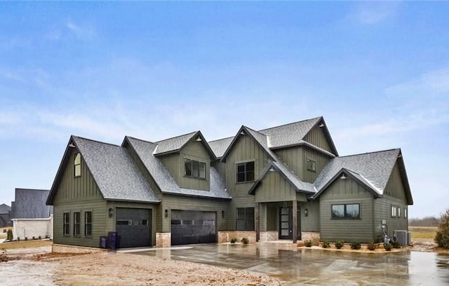 view of front of property featuring stone siding, central AC unit, board and batten siding, and roof with shingles