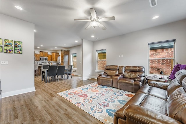 living room with light wood-style floors, baseboards, visible vents, and recessed lighting