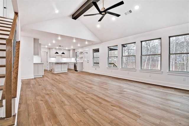 unfurnished living room with beam ceiling, light wood finished floors, visible vents, stairway, and a ceiling fan